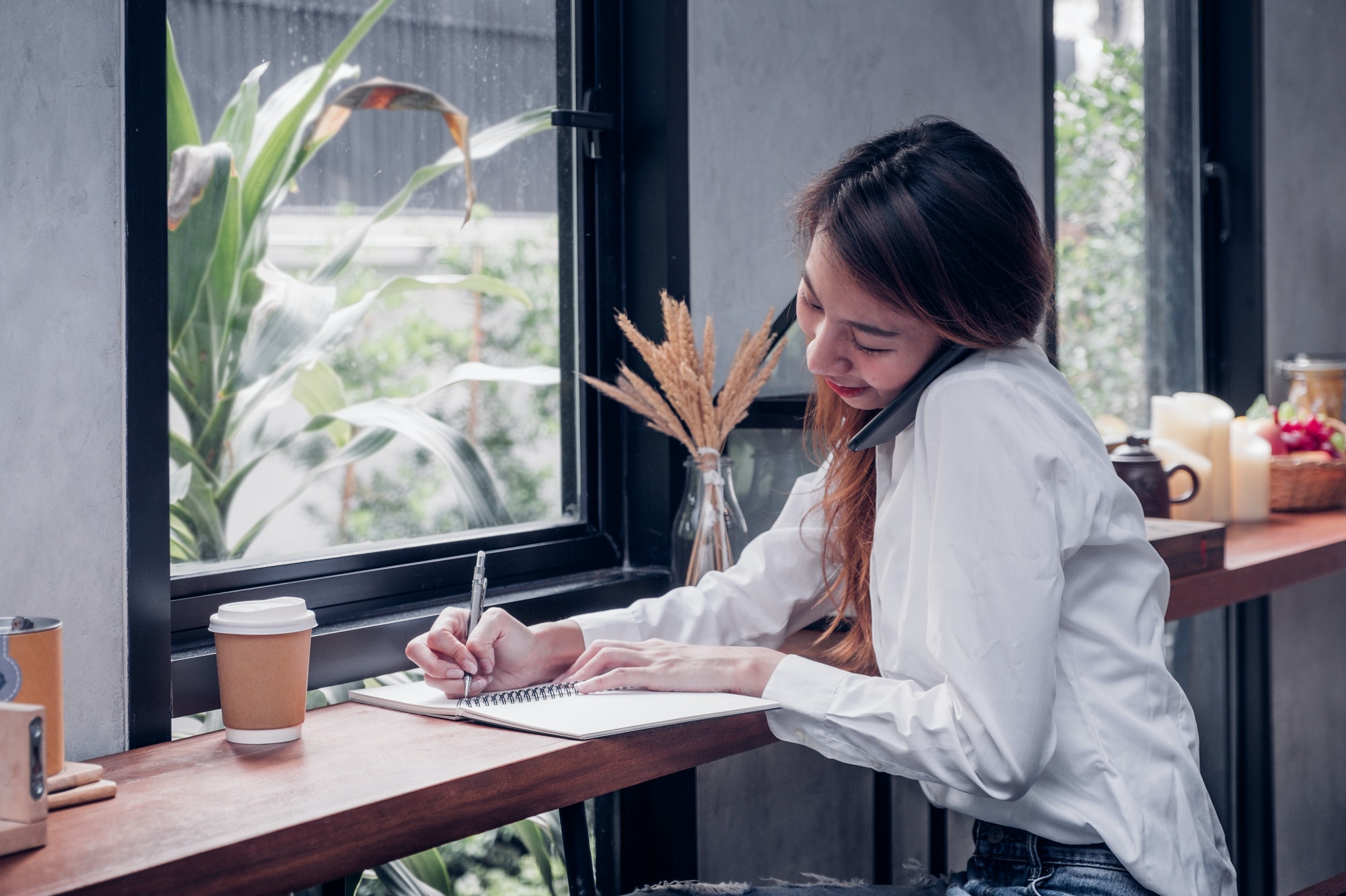 Asian Businesswoman use mobile phone contact customer and writing